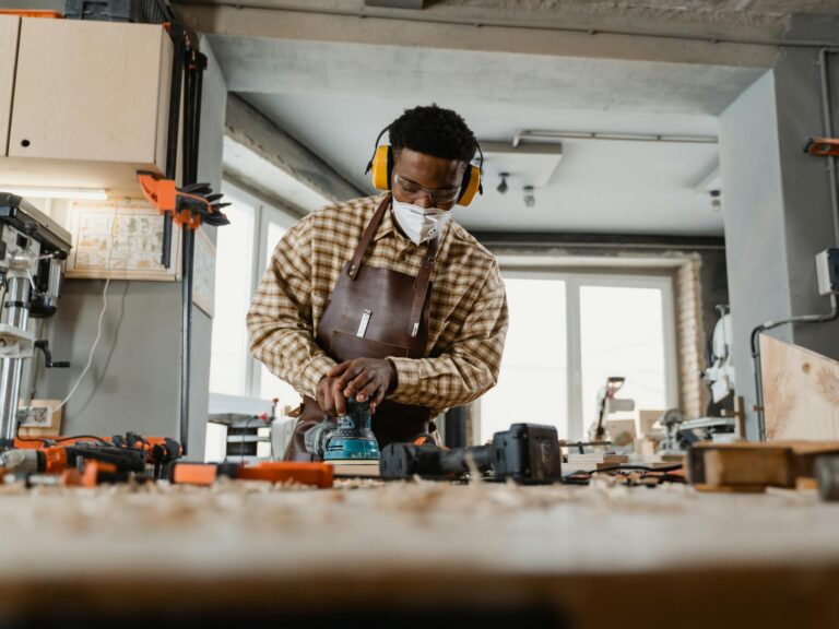 Artisan in a workshop sanding a round wooden table, showcasing the process of creating circular furniture.